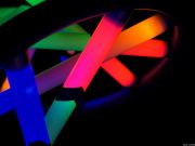 Closeup photo of DNA structure model with base pairs represented by glowing neon bars.